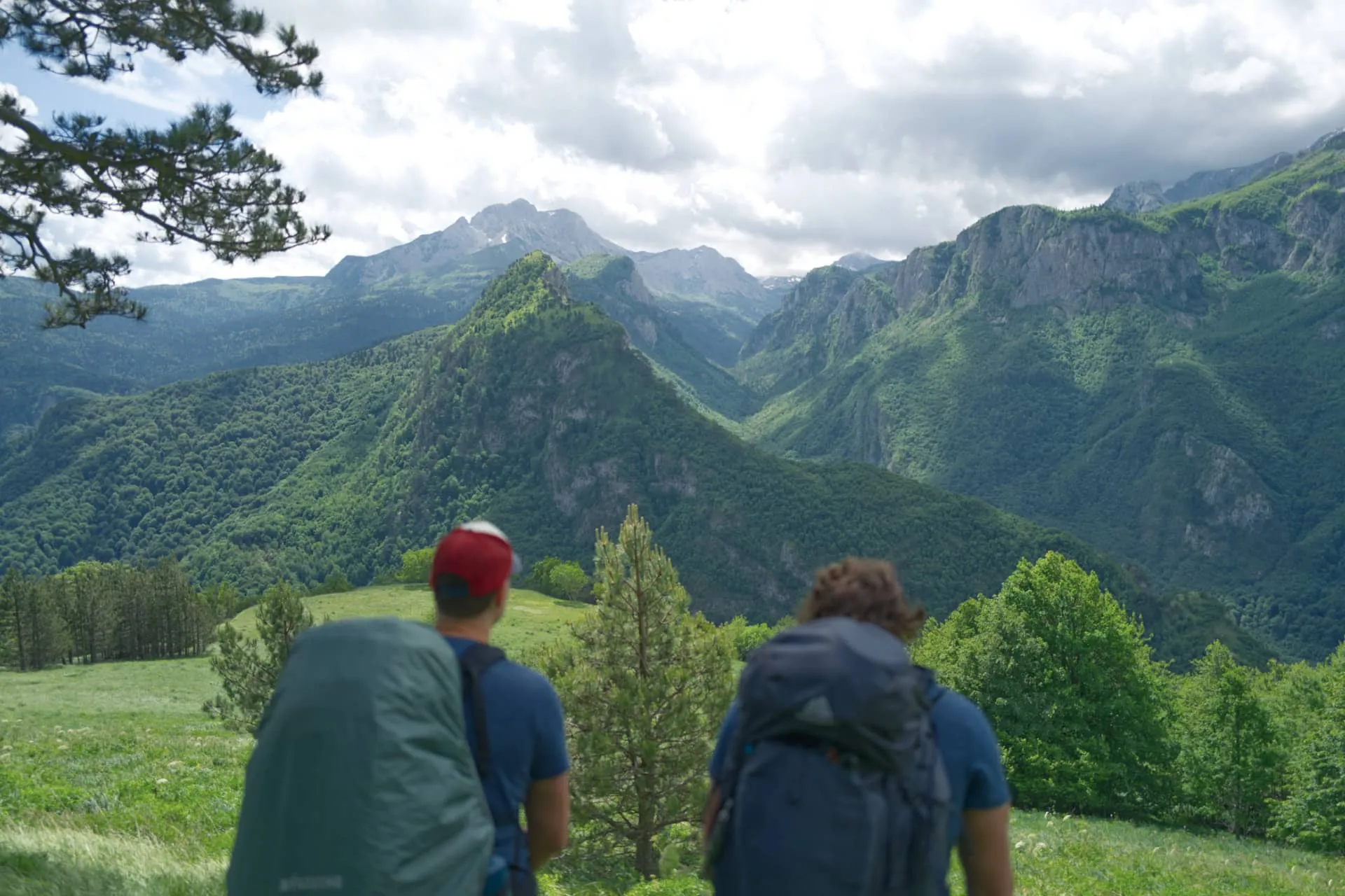 Dos senderistas contemplando el majestuoso paisaje de montaña en Sutjeska, viaje de aventura en grupo por los Balcanes.